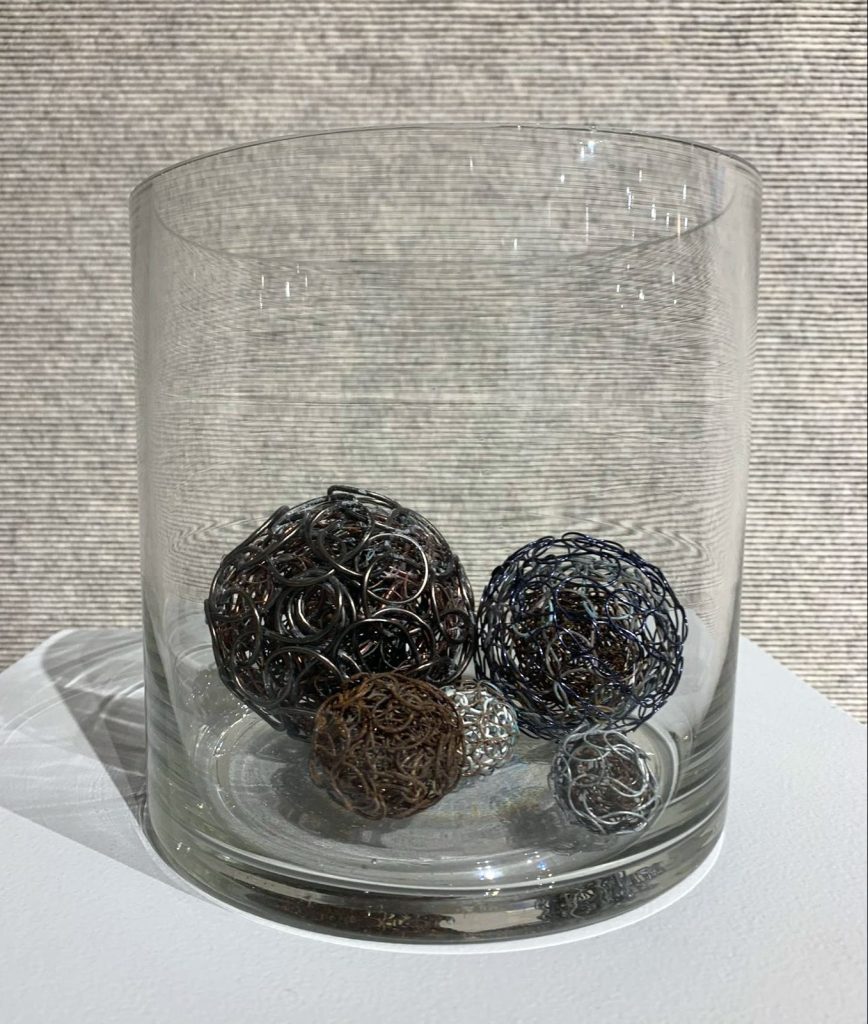 Treasure or Trouble: Polymetallic Nodules I, II, VIII-X knitted metal by Michelle Schwengel-Regala; Copper, aluminum, steel, brass, and seawater in readymade object (glass)